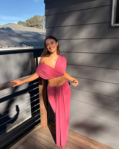 The Benni Celia Set in Rose Wine is a designer two-piece outfit featuring a gathered crop top with a versatile off-the-shoulder neckline and a matching draped maxi skirt. Crafted from soft stretch jersey in a rich rose wine hue, this elegant set is perfect for weddings, engagement parties, formal events, cocktail occasions, and special celebrations.