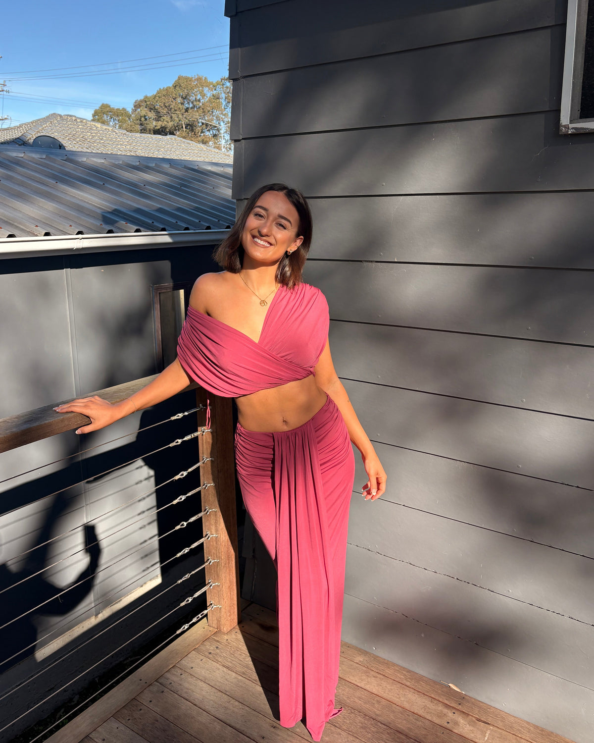 The Benni Celia Set in Rose Wine is a designer two-piece outfit featuring a gathered crop top with a versatile off-the-shoulder neckline and a matching draped maxi skirt. Crafted from soft stretch jersey in a rich rose wine hue, this elegant set is perfect for weddings, engagement parties, formal events, cocktail occasions, and special celebrations.