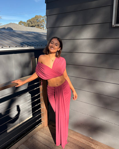 The Benni Celia Set in Rose Wine is a designer two-piece outfit featuring a gathered crop top with a versatile off-the-shoulder neckline and a matching draped maxi skirt. Crafted from soft stretch jersey in a rich rose wine hue, this elegant set is perfect for weddings, engagement parties, formal events, cocktail occasions, and special celebrations.