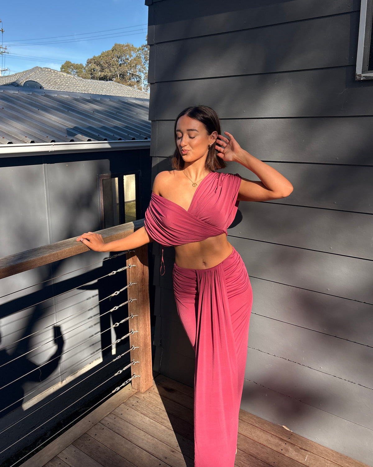 The Benni Celia Set in Rose Wine is a designer two-piece outfit featuring a gathered crop top with a versatile off-the-shoulder neckline and a matching draped maxi skirt. Crafted from soft stretch jersey in a rich rose wine hue, this elegant set is perfect for weddings, engagement parties, formal events, cocktail occasions, and special celebrations.
