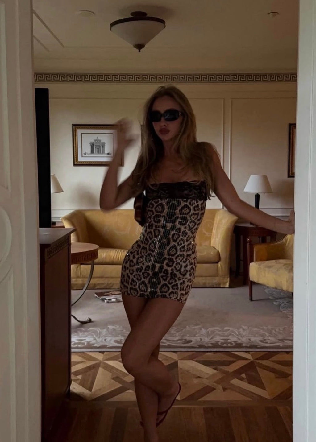 Model wearing the Mali Marea Chui Mini Dress, featuring a leopard print design, black lace-trimmed square neckline, delicate shoulder straps, a fitted corset-inspired bodice with front tie detailing and a figure-hugging mini-length silhouette.